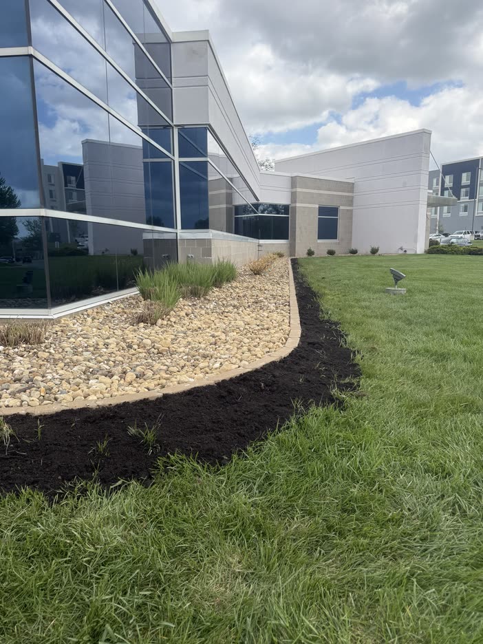 Curved mulch and rock bed along a glass office building