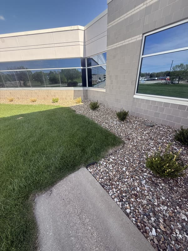 River rock bed and shrubs at the base of a glass building