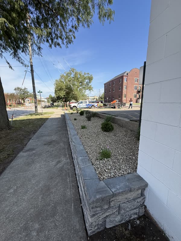 Stone wall and rock bed following a concrete sidewalk